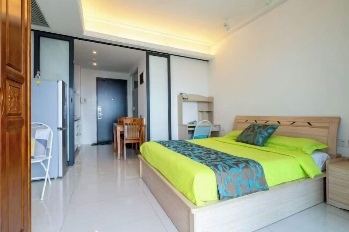 A bedroom with a bed, bedside table, and a desk with a chair.