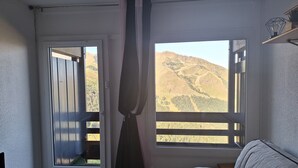 Una habitación con puerta corredera que da a un espacio exterior, ventana con vista a un paisaje montañoso y un sofá.