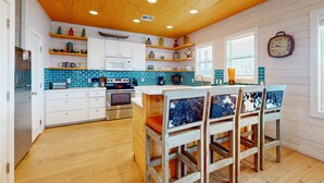 A kitchen with wooden cabinets, a microwave, and a stove. There are two chairs with patterned cushions. - OV10 Golf Cart Included, Shared Pool, Pet Friendly, Parking for 3 (Port Aransas)