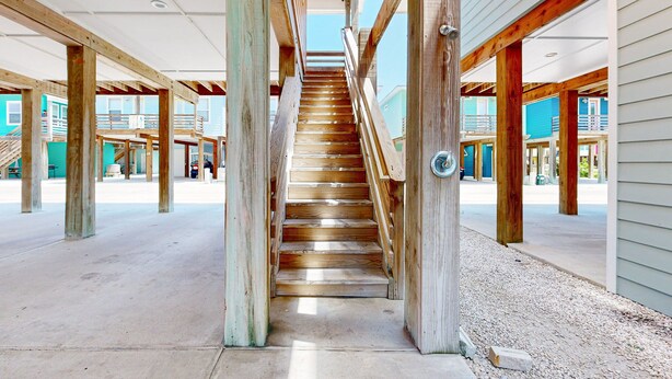A wooden staircase leading to upper levels, surrounded by wooden beams and columns, with a view of the outside. - OV10 Golf Cart Included, Shared Pool, Pet Friendly, Parking for 3 (Port Aransas)