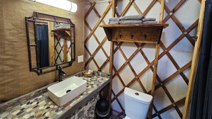 A compact bathroom with a wooden vanity, a sink, a toilet, and a mirror. - Premium Comfort in the Wilderness (Nabesna)