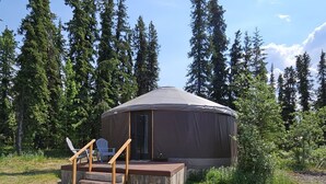 A yurt with a wooden deck and two Adirondack chairs. - Premium Comfort in the Wilderness (Nabesna)