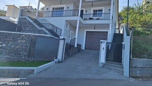 A two-story house with a stone wall, a garage, and a staircase leading to the upper floor. - Figueira's House by the Atlantic (Ponta do Sol)
