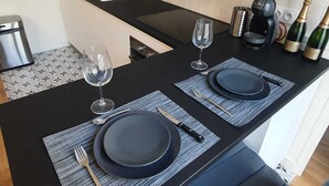 A modern kitchen with a black countertop, two sinks, a coffee machine, and wine bottles. - Saint Honoré - Luxury Apartement 1 BR (Paris)