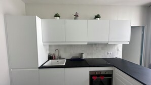 A modern kitchen with white cabinets, a black countertop, a stainless steel sink, and a built-in oven. - Saint Honoré - Luxury Apartement 1 BR (Paris)