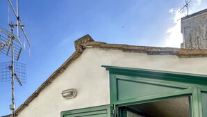 Une porte verte qui donne sur une pièce dont le sol est recouvert de carreaux et qui possède une petite fenêtre.