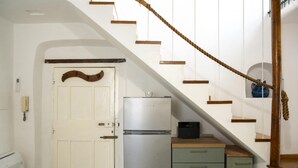 Une cuisine avec une porte blanche, un réfrigérateur argenté et un escalier en bois.