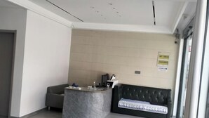 A reception area with a marble counter, a sofa, and a wall-mounted sign. - Xuancheng Qinglin Hotel (Xuancheng)