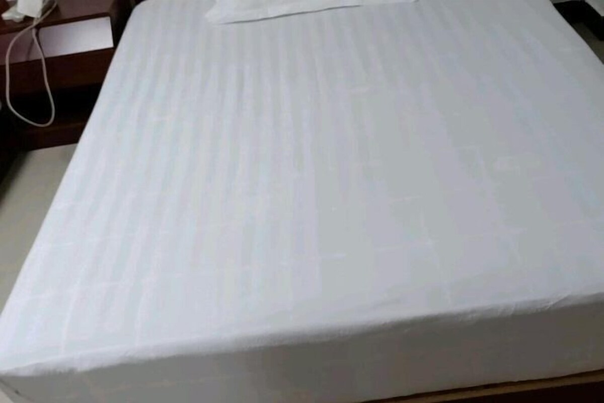 Un lit avec un matelas blanc et une tête de lit en bois.