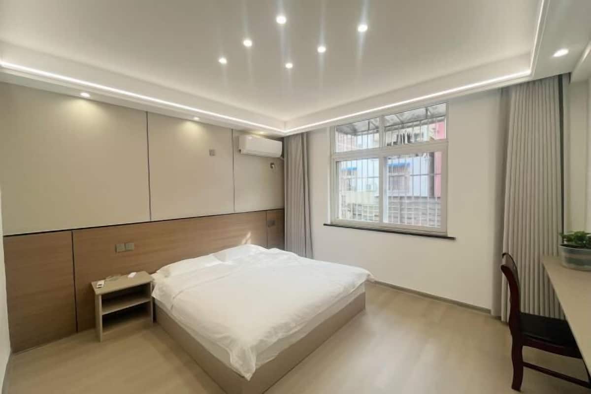 Een moderne slaapkamer met een bed, een inbouwkast en een raam met uitzicht.