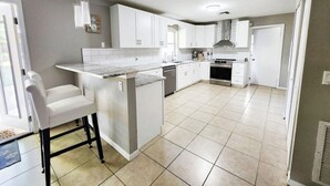 A modern kitchen with white cabinets, a central island, and a dining area with bar stools. - 3-bedroom house in charming Ocala with AC, WiFi.
Located in the heart of Ocala  (Ocala)