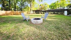 A backyard with a circular fire pit, two Adirondack chairs, and a wooden deck. - 3-bedroom house in charming Ocala with AC, WiFi.
Located in the heart of Ocala  (Ocala)