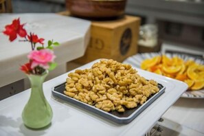 A tray of walnuts on a table with a vase of flowers and a plate of dried orange slices. - Yuting Hotel (Wenzhou)