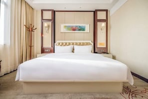 A large bed with a headboard, a bedside table, and a nightstand. There is a painting on the wall above the bed. - Yuting Hotel (Wenzhou)