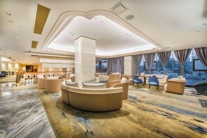 A spacious lobby with a central seating area, a high ceiling with recessed lighting, and large windows offering a view of the city. - Yuting Hotel (Wenzhou)