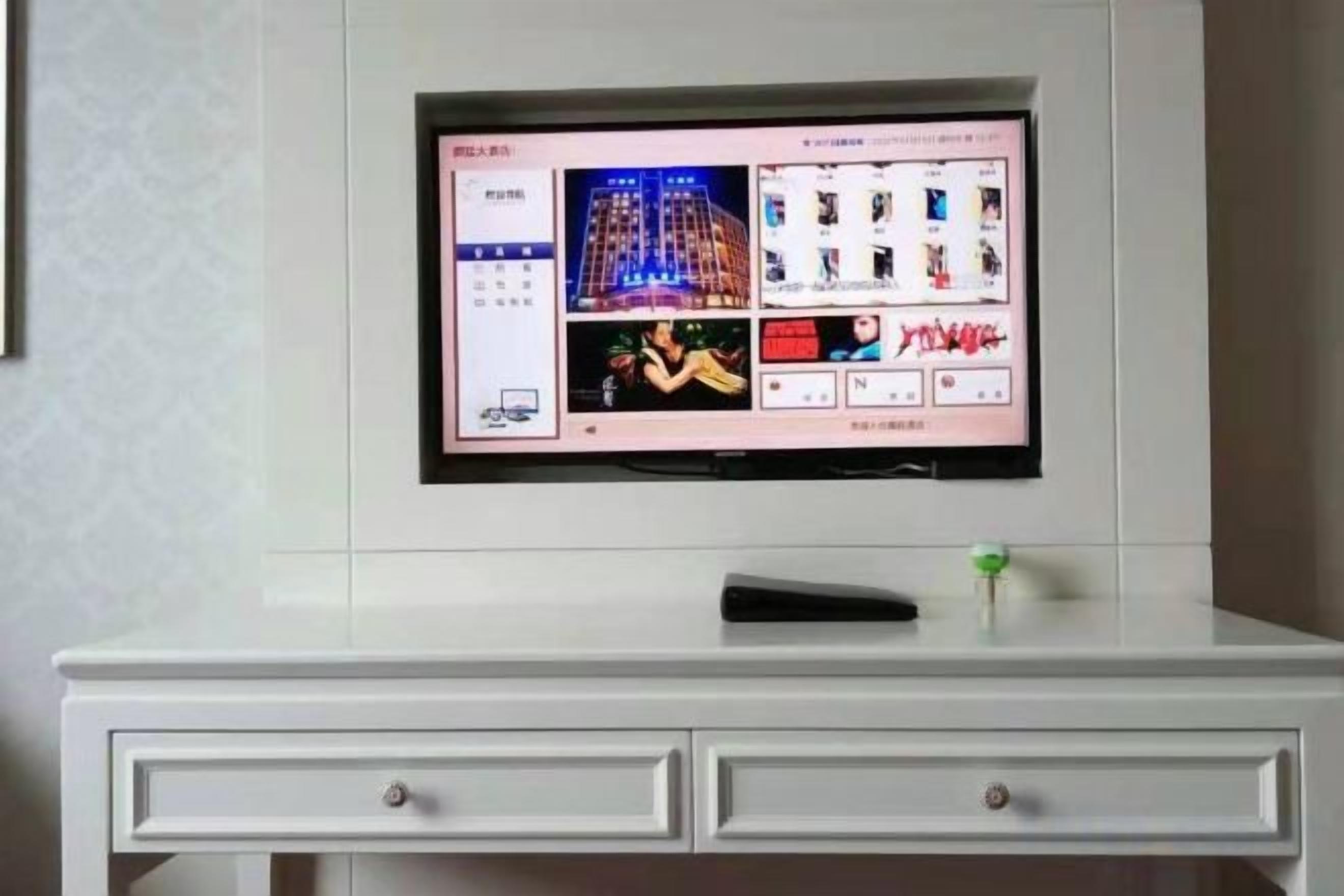Un televisor de pantalla plana montado en la pared sobre un aparador blanco con cajones.