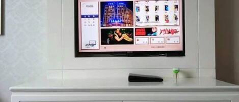Un televisor de pantalla plana montado en la pared sobre un aparador blanco con cajones.