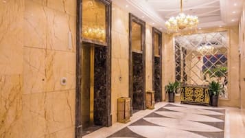 Un vestíbulo de hotel con paredes de mármol, piso estampado y un candelabro.