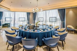 A round dining table with blue tablecloth and matching chairs, surrounded by large windows with curtains. - Yuting Hotel (Wenzhou)