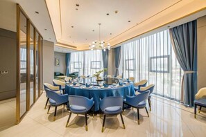 A dining area with a round table, blue chairs, and a chandelier. - Yuting Hotel (Wenzhou)