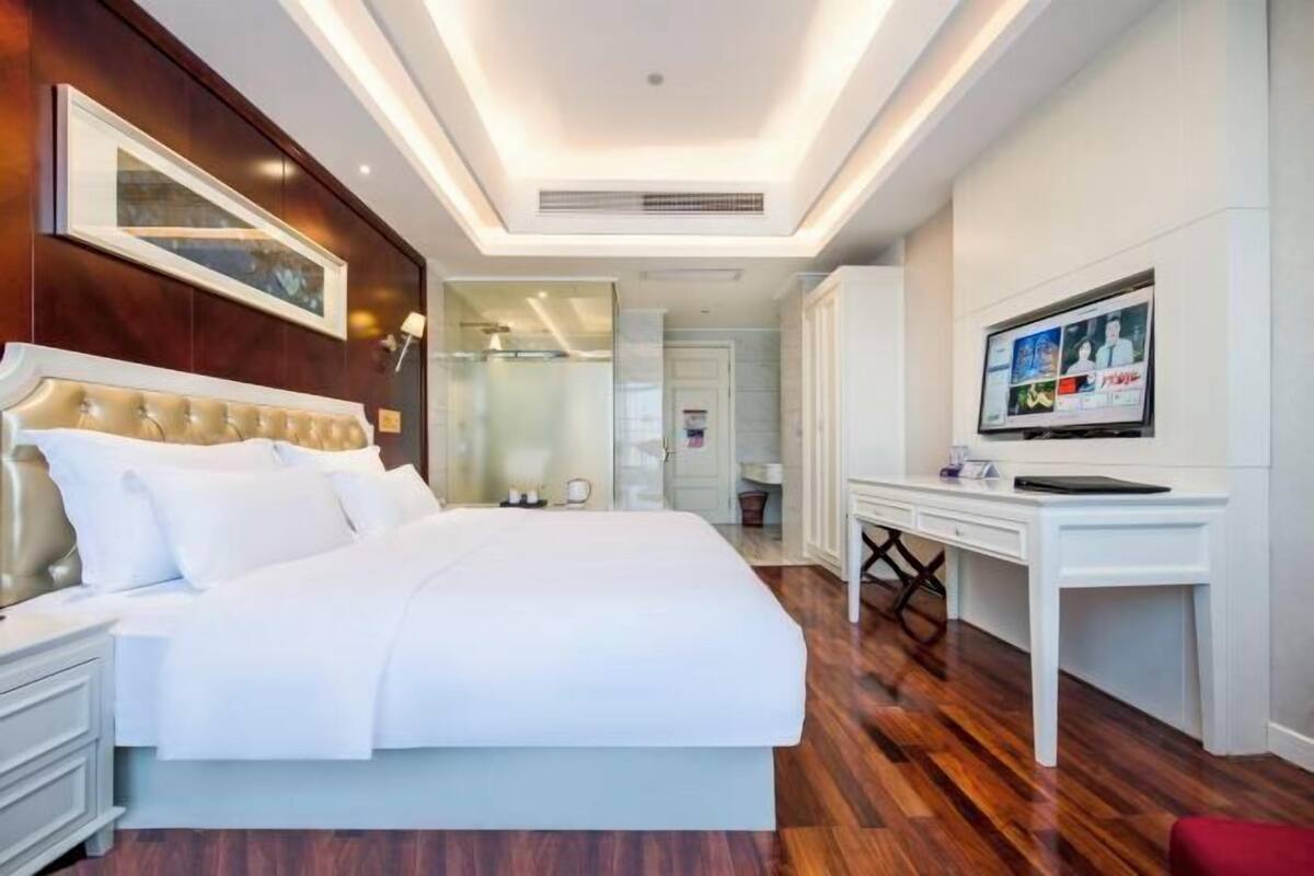 A modern hotel room with a large bed, a desk, and a television.