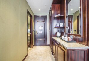 A hallway with a wooden door, a mirror, and a countertop with kitchen items. - Yuting Hotel (Wenzhou)