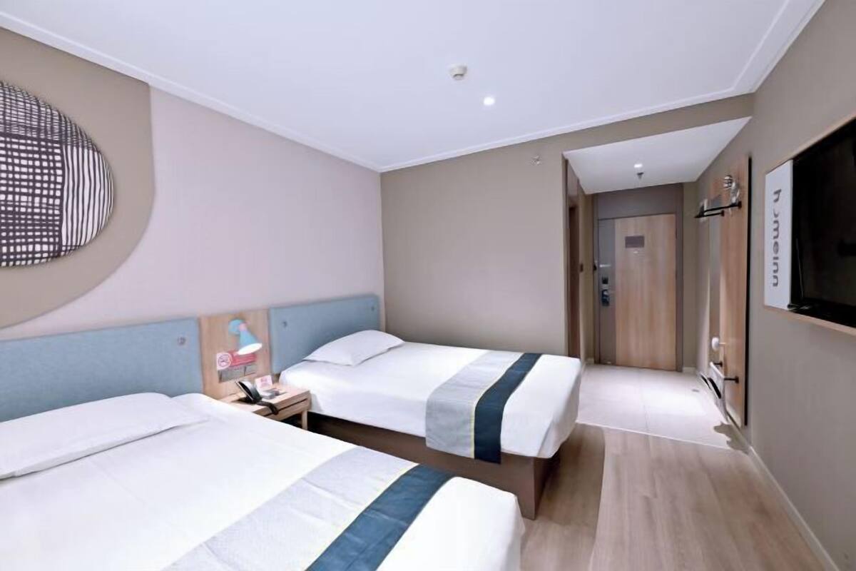A hotel room with two beds, a TV, and a bathroom door.