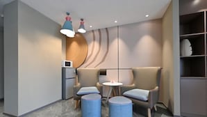 A modern waiting area with two cushioned chairs, a small table, and a round ottoman. - Homeinn Hotel (Beijing Shaoyaoju University of International Business and Economics) (Beijing)