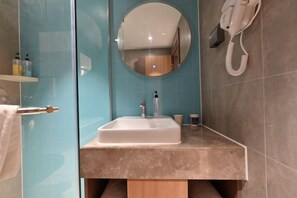 A bathroom with a white sink, a round mirror, and a hairdryer mounted on the wall. - Homeinn Hotel (Beijing Shaoyaoju University of International Business and Economics) (Beijing)