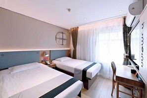 Habitación de hotel con dos camas, un escritorio, una silla y un amplio ventanal con cortinas.