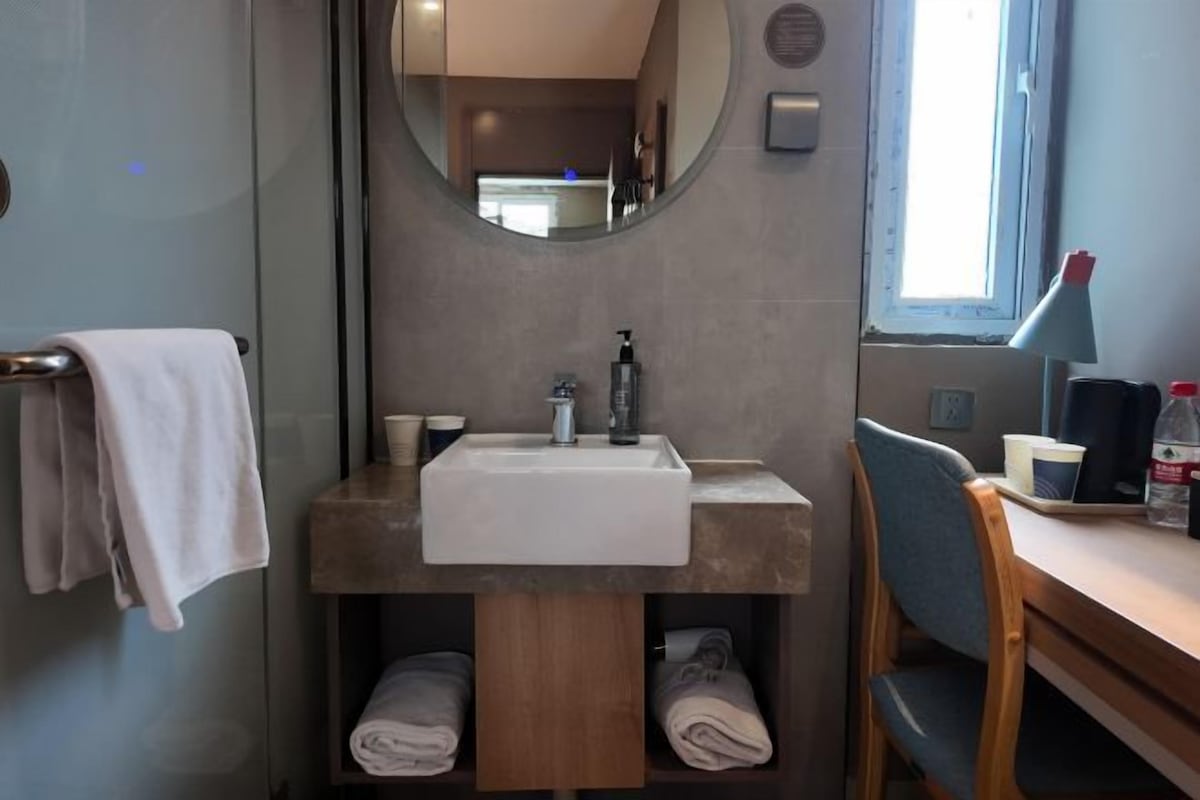 A bathroom with a sink, mirror, towel rack, and a window.