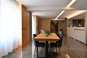 Un salón de conferencias de hotel con una larga mesa, sillas, un mostrador de recepción y una planta sobre la mesa.
