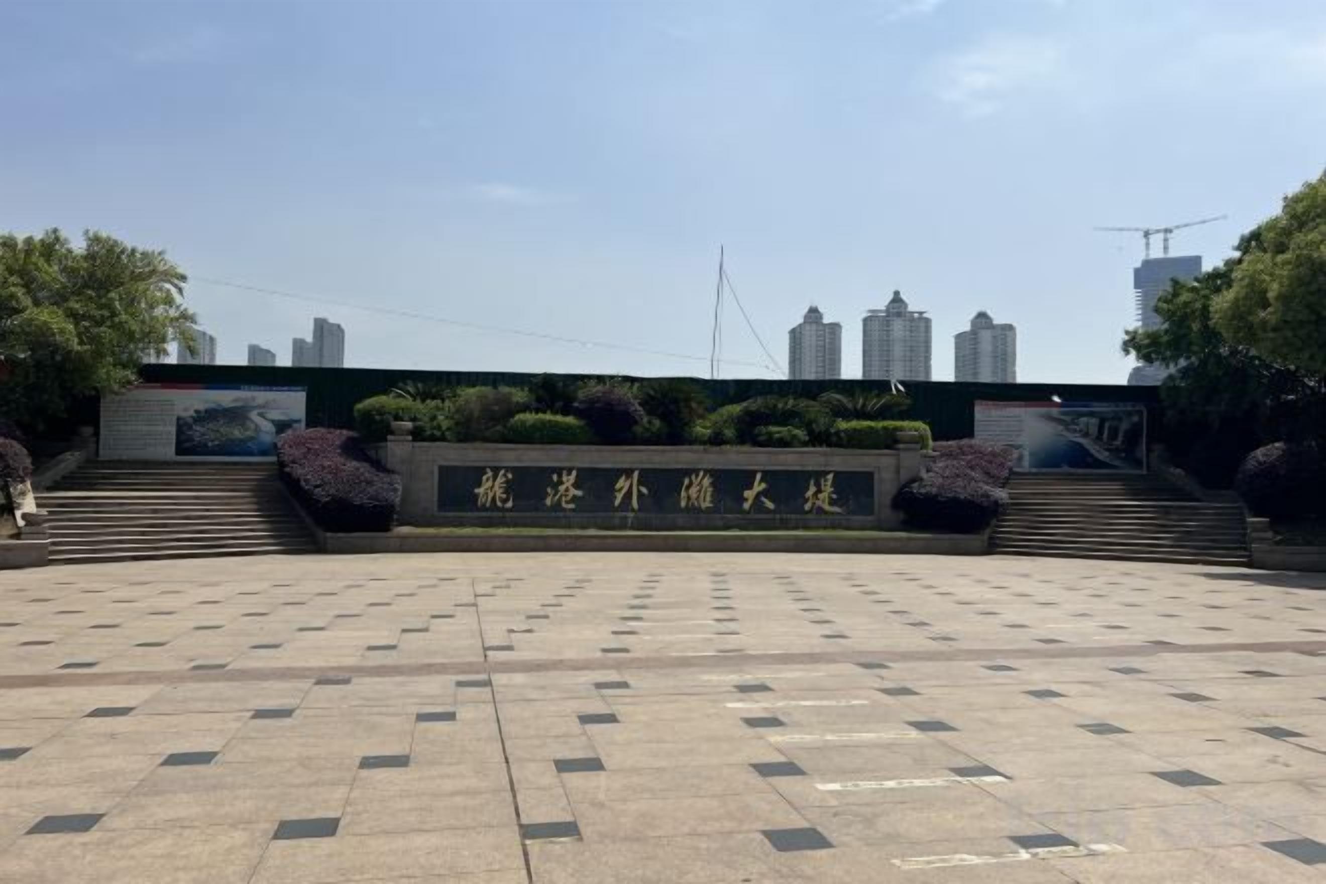 A paved plaza with a stone wall and steps leading to a building entrance.