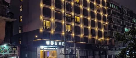 A multi-story building with illuminated windows and a storefront at the ground level.