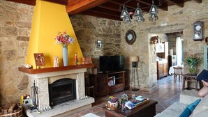 A cozy living room with a stone fireplace, a television, and a coffee table with magazines. - CASA DE COSTOIA (Ames)