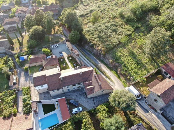An aerial view of a residential area with houses, a swimming pool, and a road. - CASA DE COSTOIA (Ames)