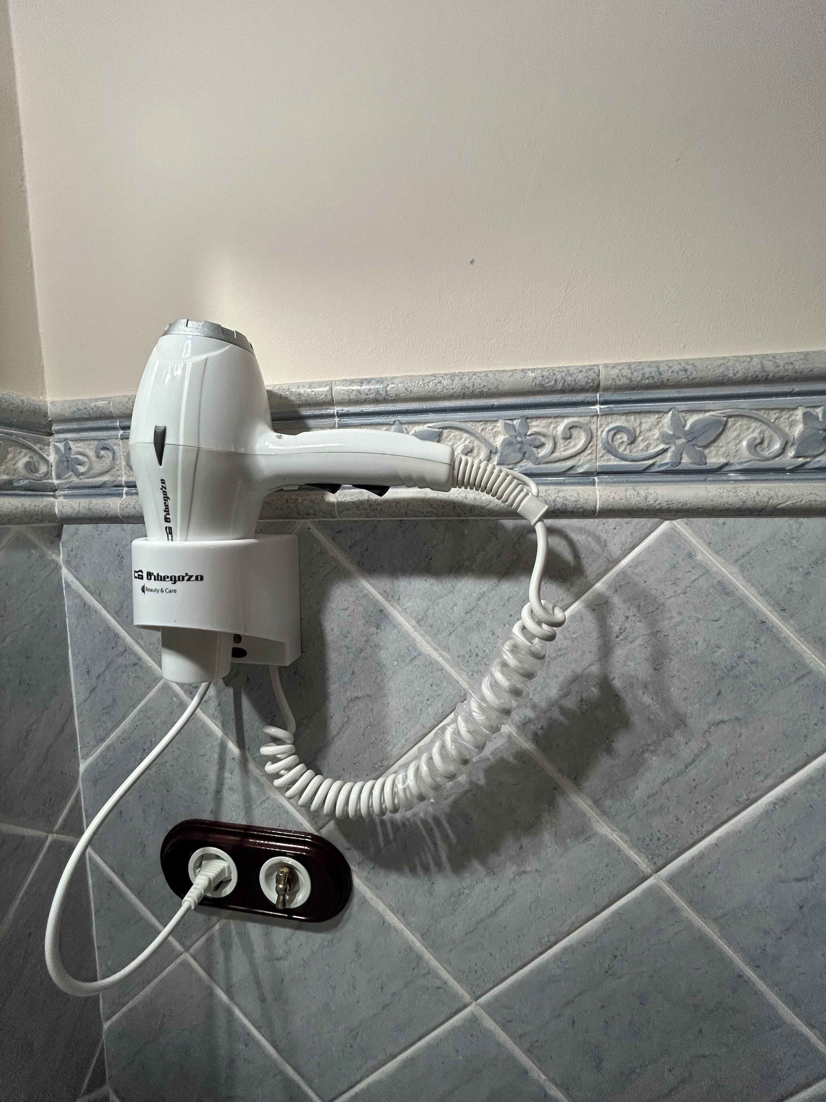 Un secador de pelo conectado a un enchufe con cable.