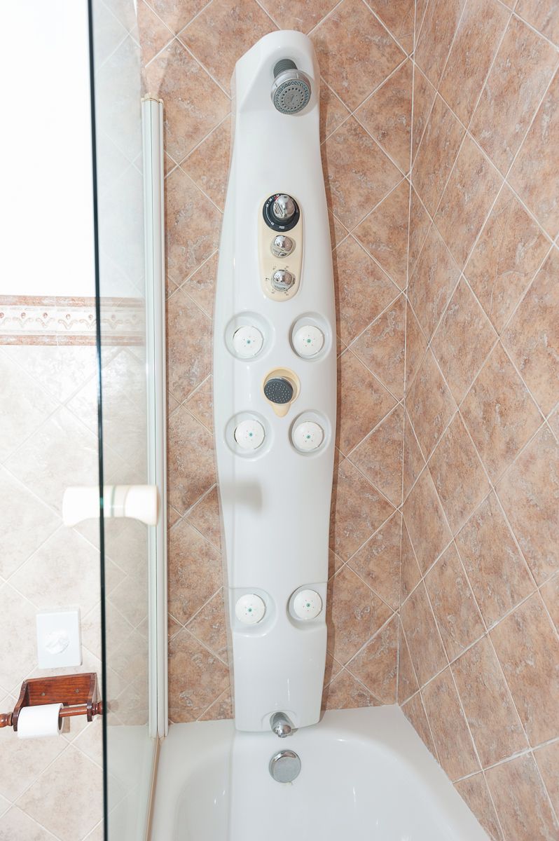 A modern bathroom with a freestanding bathtub, a glass shower enclosure, and a marble-tiled wall.