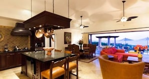 A spacious living area with a kitchen island, dining table, and comfortable seating. - Stunning 3 Bedroom Villa condo-style Ocen View, Private Chef & Butler Service (Cabo San Lucas)