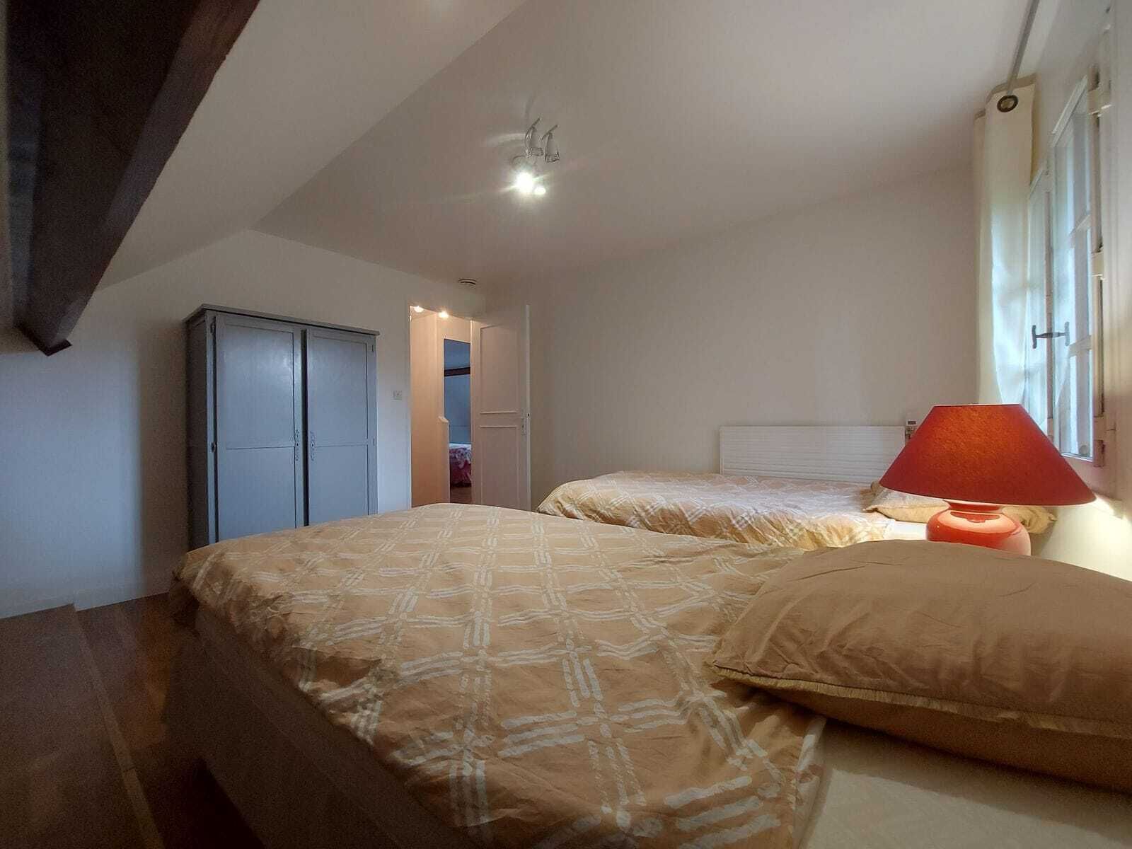 A bedroom with two beds, a wardrobe, a red lamp, and a ceiling light.