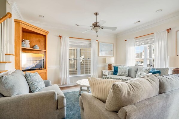 A living room with a sofa, a coffee table, a TV, and a ceiling fan. - MH22b | Ocean View 4BR w/ Huge Deck | Steps to Sand! Comp Golf Cart (Myrtle Beach)