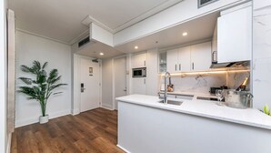 Eine moderne Küche mit weißen Schränken, einer Edelstahl-Spüle und einer Marmor-Spritzschutzwand.