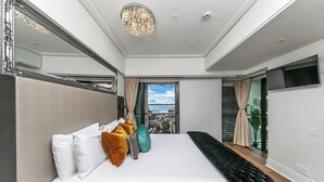 Ein modernes Schlafzimmer mit einem großen Bett, Blick ins Freie und einer Kristallleuchter.