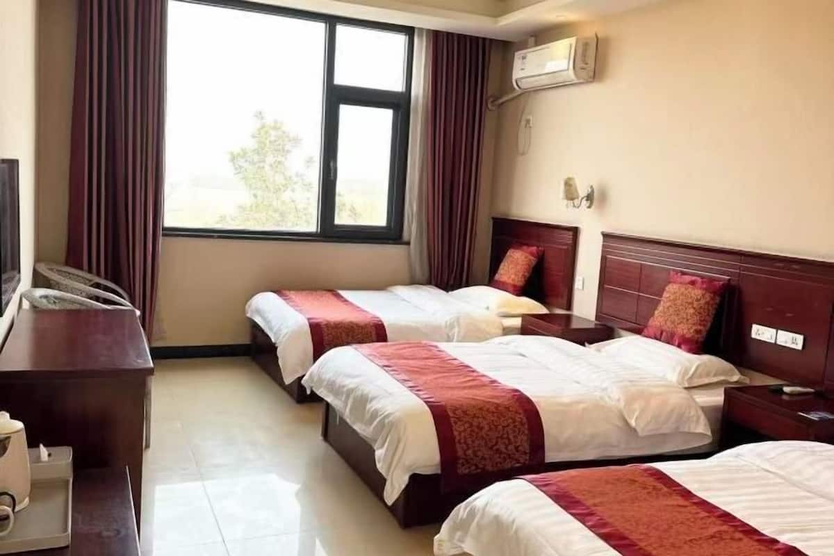 Habitación de hotel con dos camas, un escritorio, aire acondicionado y una ventana con cortinas.