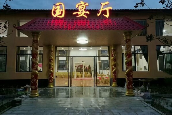 A hotel entrance with a red awning, glass doors, and golden pillars. - Neixiang Zhengyuan Business Hotel (Neixiang)