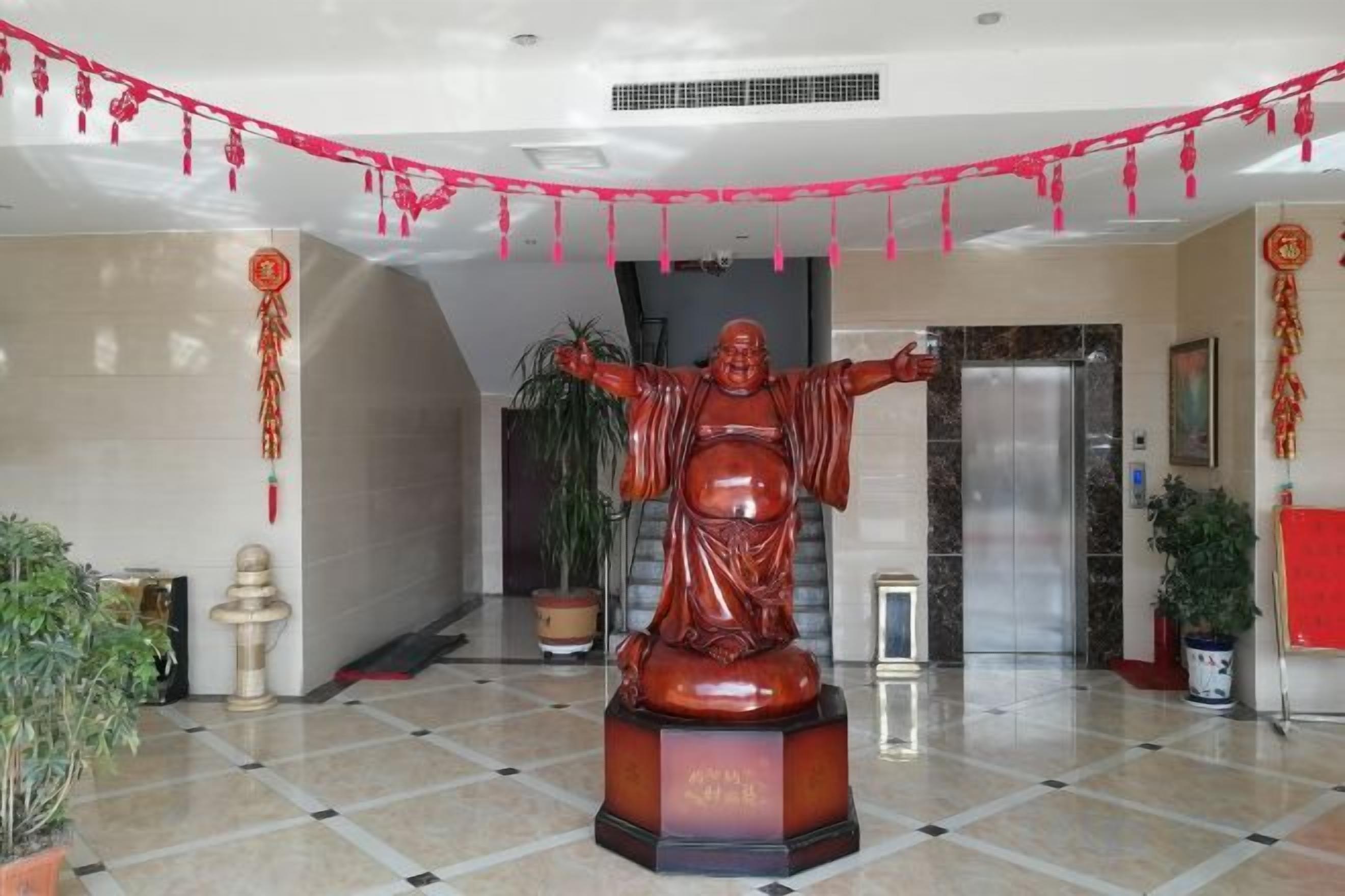 Una estatua en un vestíbulo con piso de baldosas, plantas en macetas y una máquina expendedora.