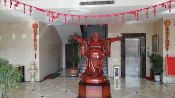Una estatua en un vestíbulo con piso de baldosas, plantas en macetas y una máquina expendedora.
