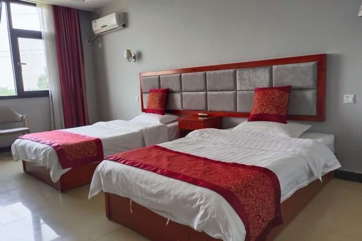 Habitación de hotel con dos camas, un ventanal grande y una decoración en tonos rojo y blanco.