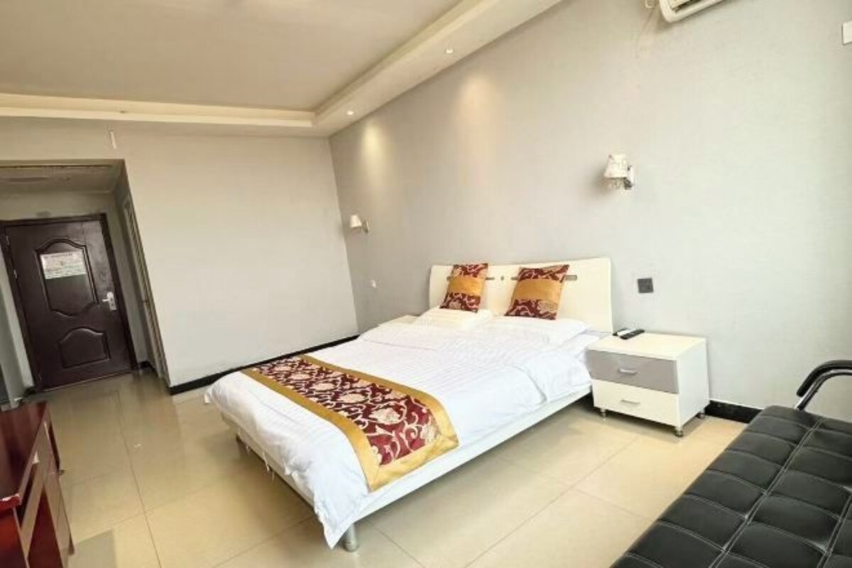 Una habitación de hotel con cama, mesita de noche, silla y puerta.