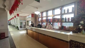 A hotel reception area with a counter, a window with a view, and a sign indicating an exit.